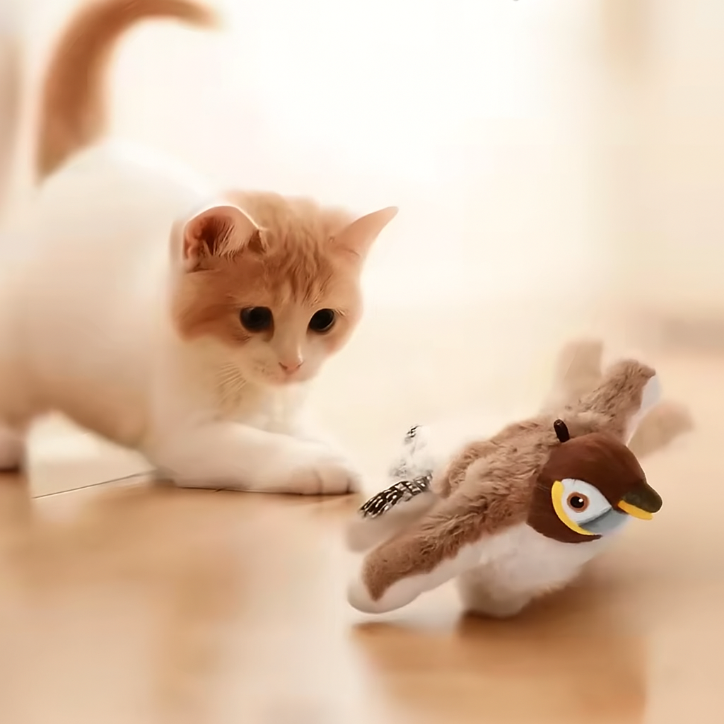Cat playing with a toy penguin on a soft surface